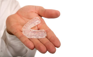 hand holding a clear teeth aligner