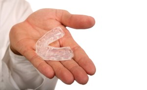 hand holding a clear teeth aligner